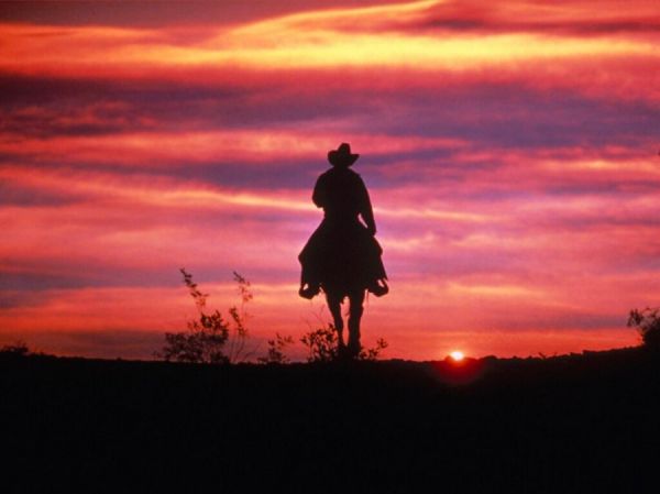 Cowboy reitet den Sonnenuntergang entgegen